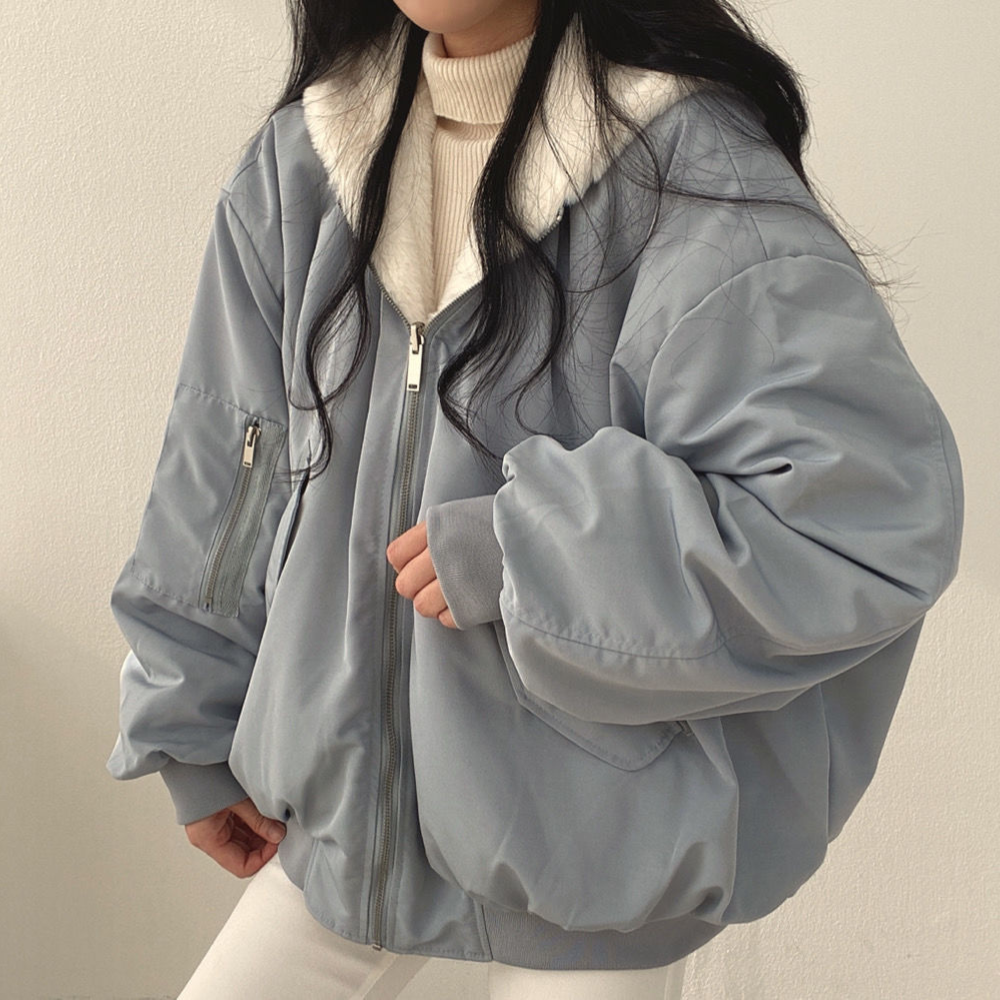 Seitenansicht einer Frau, die eine blaue Wendejacke mit Kapuze, Reißverschluss und Tasche trägt