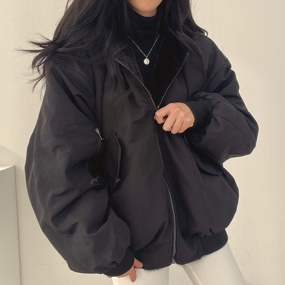 Nahaufnahme einer Frau, die eine beige Wendejacke mit Kapuze, Reißverschluss und Tasche trägt